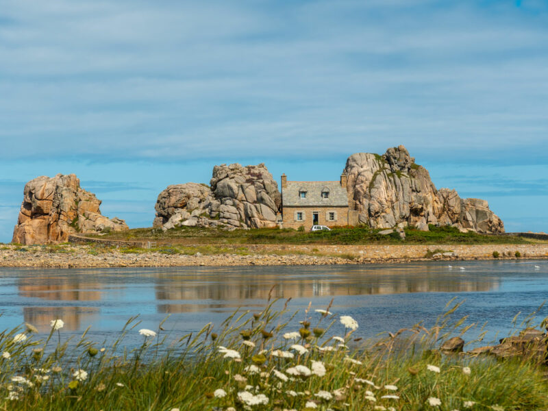 Une maison au milieu des rochers à côté d'un magnifique lac