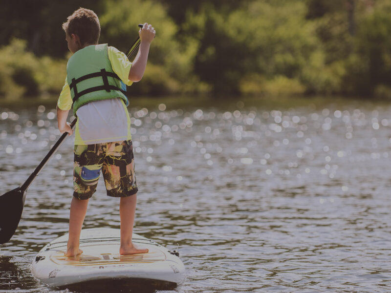 Un enfant s'exerçant au paddle sur une rivière en bretagne